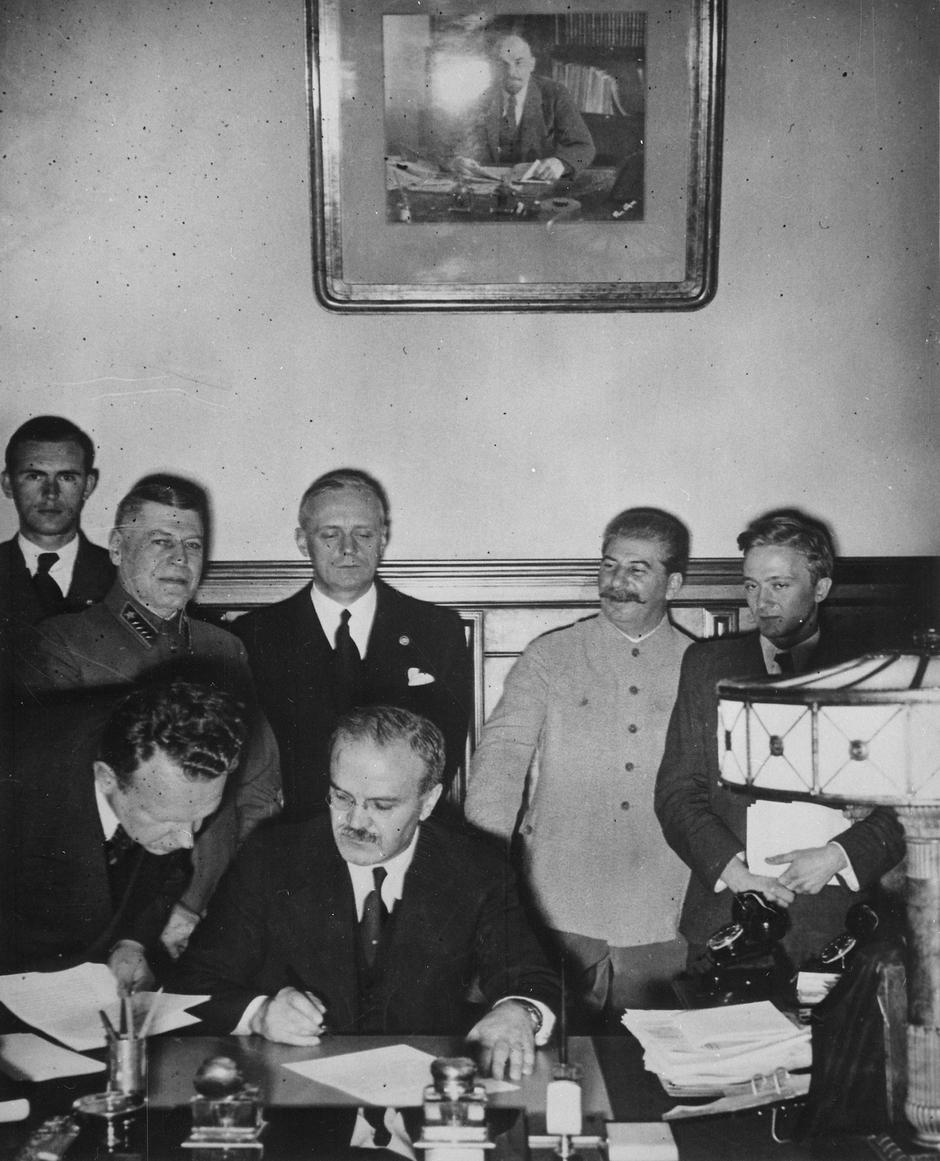 Molotov potpisuje njemačko-sovjetski sporazum o nenapadanju (Moskva, 23. kolovoza 1939. godine). U pozadini stoje Šapošnjikov, Ribbentrop i Staljin